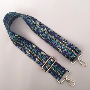 Macro detail of wide ethnic geometric fabric bag strap with golden metal lobster clasps