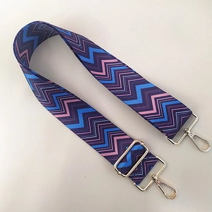Detail of wide adjustable shoulder strap with colorful zigzag pattern and gold metal hooks