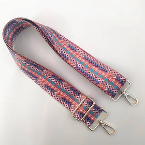 Close-up of ethnic style woven bag strap with colorful geometric patterns and gold clips