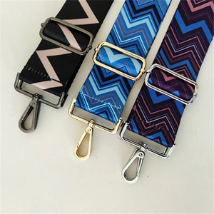 Close-up of three woven geometric pattern wide bag straps with adjustable metal buckles