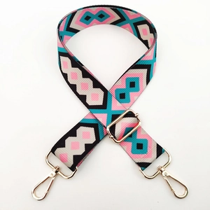 Close-up of geometric pattern shoulder strap with gold metal buckles on white background