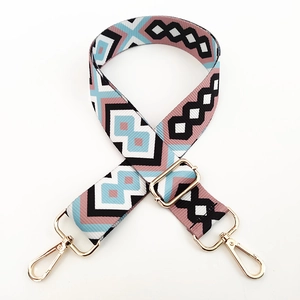 Detail view of ethnic geometric pattern bag strap with gold lobster clasps and metal buckle