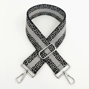 Close-up of wide polka dot bag strap with gray stripe and silver lobster clasps
