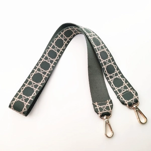 Macro detail of wide dark green woven shoulder strap with gold metal lobster clasps