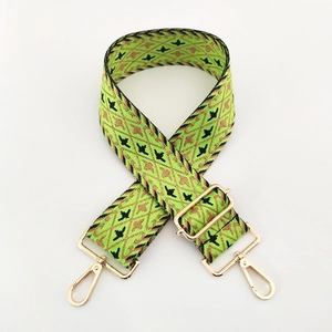Detail of wide jacquard nylon bag strap with green geometric pattern and gold swivel hooks