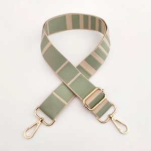 Macro detail of adjustable striped green and beige bag strap with gold metal hooks