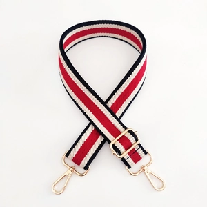 Détail de la bandoulière en toile rayée rouge noir blanc avec mousquetons dorés chic