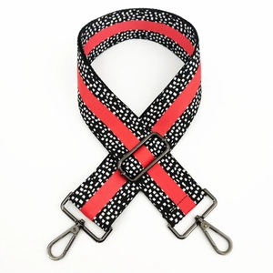 Detail of adjustable wide bag strap with red stripes and dark metal swivel hooks