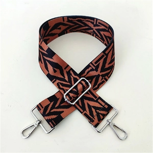 Macro detail of brown and black geometric woven strap with silver metal swivel hooks