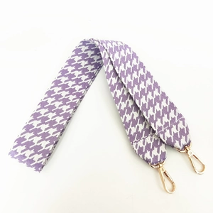 Detail of purple and white houndstooth bag strap with gold rotating metal hooks