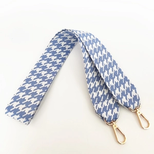 Detailed view of the blue and white houndstooth wide bag strap with gold metal lobster hooks
