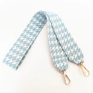 Detail of wide light blue houndstooth canvas strap with gold metal lobster clasps