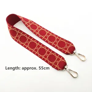 Close-up of red and beige geometric canvas strap with golden metal lobster clasps