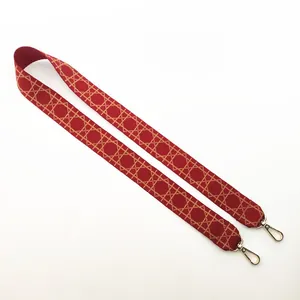 Detail of red and gold geometric jacquard bag strap with metal carabiner clips