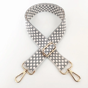 Close-up of jacquard embroidery wide shoulder strap with gold metal lobster clasps