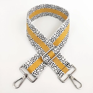 Detail of adjustable wide bag strap with yellow stripes and black pixel pattern hardware