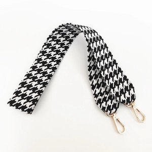 Close-up of black and white houndstooth canvas bag strap with golden metal lobster clasps