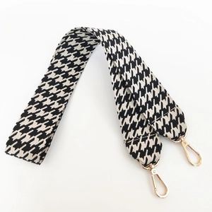 Close-up of black and white houndstooth wide bag strap with gold lobster clasps