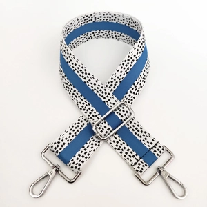 Detail of adjustable blue and black spotted canvas bag strap with silver metal swivel hooks