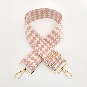Detail des rosa Hahnentritt-Taschenriemens mit verstellbaren goldfarbenen Metallschnallen