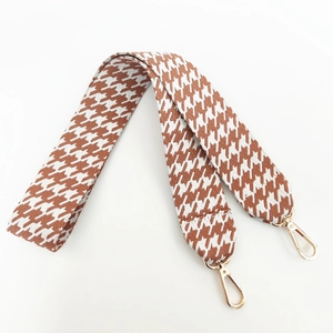 Macro detail of houndstooth woven replacement strap with golden metal lobster clasps
