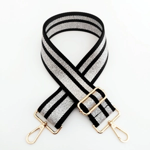 Close-up of wide woven shoulder strap with silver lines and gold lobster clasps