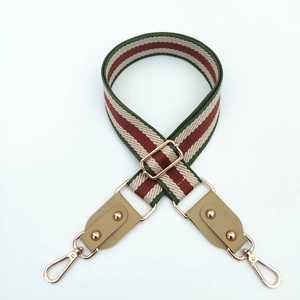 Detail of adjustable wide striped strap with leather ends and gold metal lobster clasps