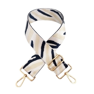Close-up of zebra pattern woven bag strap with glossy gold metal spring hooks