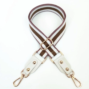 Detail of striped brown and white woven shoulder strap with gold metal hooks