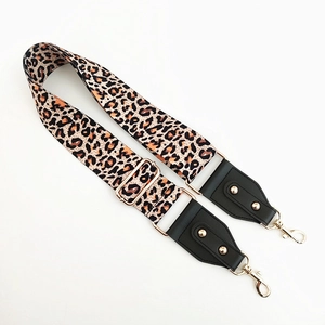 Close-up of leopard print bag strap with golden metal hooks and black leather ends