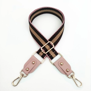 Detail of colorful striped wide bag strap with pink leather and gold metal hooks
