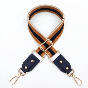 Detail of adjustable wide woven bag strap with retro stripes and golden metal hooks