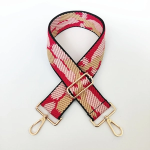 Close-up of a 5cm wide adjustable bag strap with red and pink geometric stripes and gold buckles