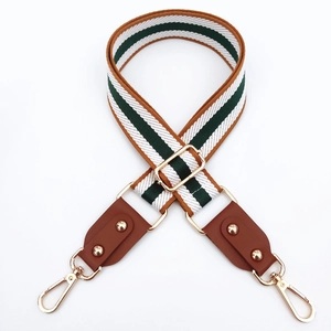 Close-up of adjustable striped canvas bag strap with leather ends and gold hardware