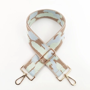 Detail of wide jacquard shoulder strap with geometric pattern and golden metal clips