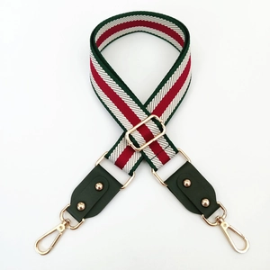 Close-up of adjustable striped bag strap with green red white weave and gold buckles