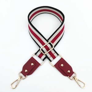 Detailed view of red and black striped canvas strap with gold hardware and leather ends