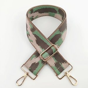 Macro detail of geometric camouflage woven strap with polished gold-tone metal snap hooks