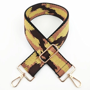 Close-up of adjustable wide woven bag strap with geometric patterns and gold metal clips