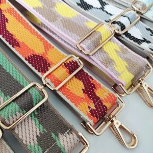 Detailed view of colorful geometric woven bag straps with golden metal hooks and buckles