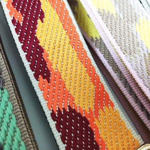 Close-up of diverse wide woven straps featuring colorful geometric jacquard patterns
