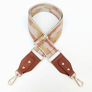 Close-up of geometric woven wide bag strap with brown leather and gold hardware