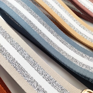 Macro detail of striped woven bag straps with silver metallic glitter and gold hardware