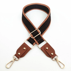Detail of adjustable woven bag strap with geometric patterns and gold metal lobster clasps