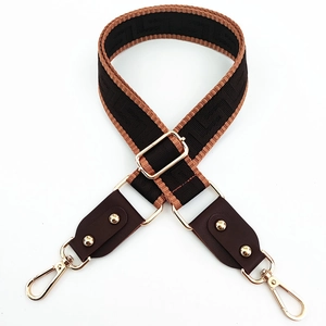 Detail of adjustable wide nylon shoulder strap with brown geometric pattern and gold hooks