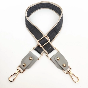 Detail of adjustable geometric pattern wide bag strap with gold rotating metal hooks