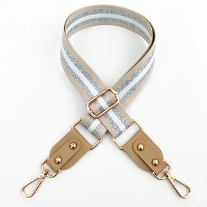 Detail view of beige bag strap with silver metallic stripes and gold lobster clasps