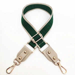 Detail of green meander jacquard bag strap with gold metal hooks and leather ends
