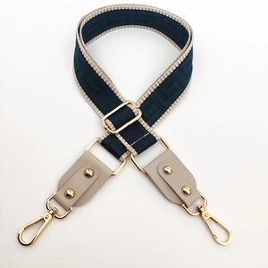 Macro detail of adjustable nylon bag strap with navy geometric pattern and gold hardware
