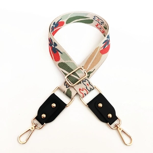Detail of floral embroidery bag strap with gold rivets and metallic swivel hooks
